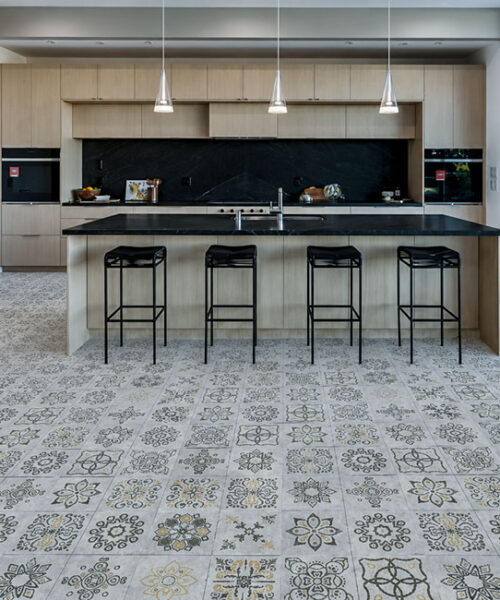 Classic Porcelain - 19/64" (7.5mm) - Swiss Techslate (MCPor7.5) Classic Porcelain Swiss TechSlate click-lock flooring in light gray with printed floral medallions in a bright modern kitchen with island stools.