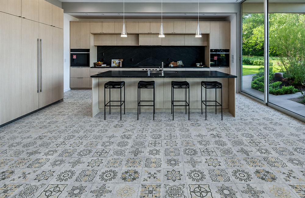 Classic Porcelain - 19/64" (7.5mm) - Swiss Techslate (MCPor7.5) Classic Porcelain Swiss TechSlate click-lock flooring in light gray with printed floral medallions in a bright modern kitchen with island stools.