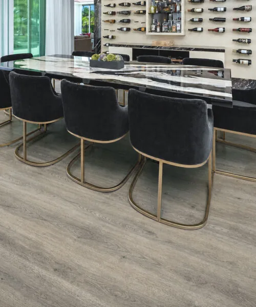 Elegant dining and wine room with gray wood-grain cork flooring and dark velvet chairs.